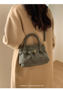 Detail of dark grey suede tote bag with gold hardware and stylish buckle strap design