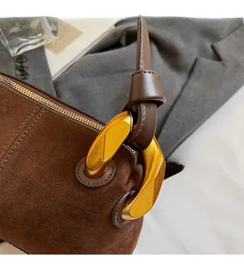 Close-up of premium gold-toned metal hardware on a brown suede Boston handbag