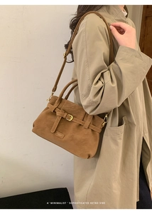 Detail of brown suede handbag with leather buckle and antique bronze hardware accents