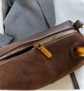 Detailed close-up of smooth gold-tone zipper on a dark brown suede Boston bag