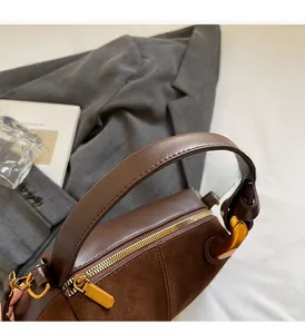Detail of dark brown leather Boston bag showing gold zipper and textured handle attachment