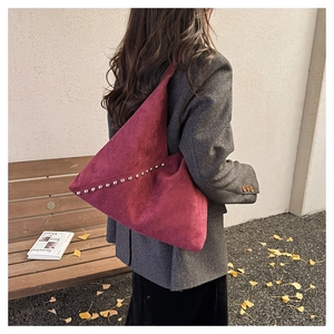 Detail of burgundy matte suede triangle bag with stylish silver metal rivets on the side