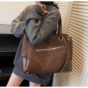 Dettagli di cuciture intrecciate a mano e rivetti argentati su borsa tote marrone scuro