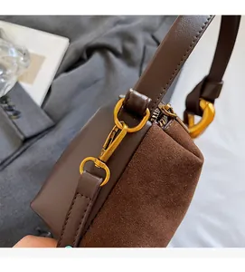 Close-up of brown leather stitching and gold hardware on a vintage crossbody pillow bag
