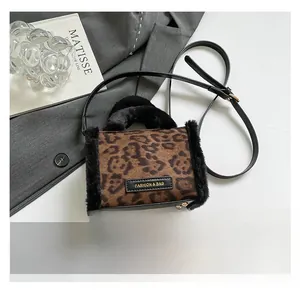 Détail d'un sac cabas à imprimé léopard avec bordure en fausse fourrure et badge doré
