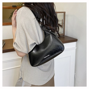 Close-up of black glossy leather hobo bag with white Fashion & Bags text on shoulder