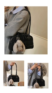 Detailed view of black nylon tote bag with white contrast stitching and plush rabbit charm