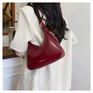 Detail of red crescent underarm bag with silver buckle and adjustable strap on a model