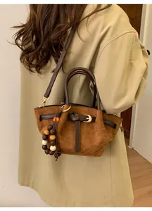 Détail du sac cabas en daim marron avec lanières en cuir et perles en bois décoratives