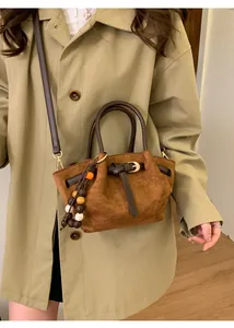 Détail du sac à main en daim marron avec pendentif en perles et boucle élégante