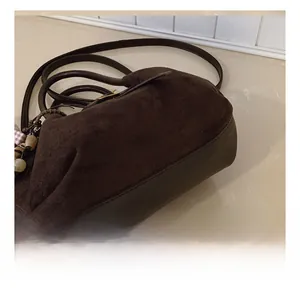 Detalle de costuras finas y textura de ante en la parte inferior de este bolso marrón