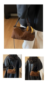 Macro view of brown suede Boston bag featuring chunky gold rings and smooth leather strap
