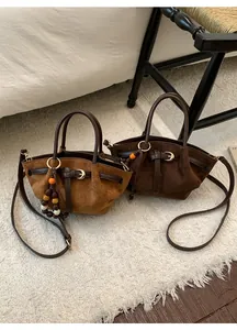 Détail du cabas en suède avec garniture en cuir marron et pendentif en perles ethniques