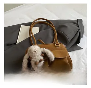 Retro brown leather pillow bag with twin flap pockets and a plush bunny charm on white fabric