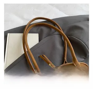 Detail showing smooth suede handle and metal rings of the brown shoulder bag