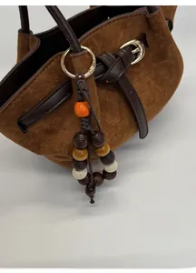 Détail de breloque en perles multicolores avec crochet doré sur sac en daim brun