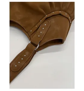 Detail of silver rivets and ring buckle on a brown leather shoulder bag with stitching