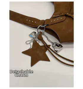 Detail of brown leather tote featuring a detachable star charm and silver heart pendant