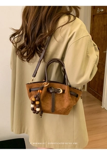 Detail of a brown faux suede handbag with decorative wooden beads and a retro strap