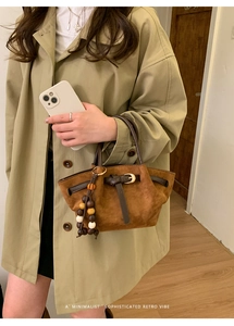 Gros plan d'un sac à main rétro en daim marron avec lanières en cuir et perles en bois