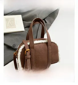 Detail of brown suede Boston bag with white faux fur trim and gold metal buckle hardware
