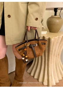 Détail d'un sac à main en daim marron avec lanières en cuir et perles décoratives