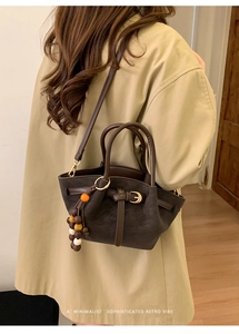 Détail du sac cabas mat marron foncé avec pendentif perlé et lanières en cuir