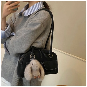 Detail of vintage black suede pillow bag with contrast stitching and rabbit plush charm