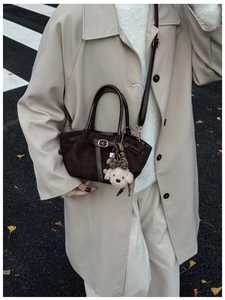 Detalle de bolso tote de ante marrón oscuro con un lindo adorno de perro de peluche