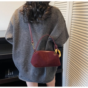 Detail of burgundy suede Boston bag with gold ring hardware and thin shoulder strap