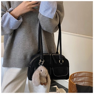 Detail of vintage black pillow bag with white contrast stitching and plush rabbit charm