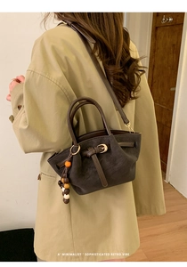 Détail d'un sac cabas en daim marron foncé avec charm en bois et anses en cuir