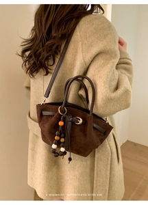 Vue détaillée de la texture en daim marron foncé et des perles de bois sur le sac à main