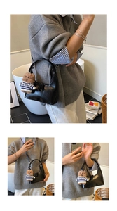 Détail du sac croissant noir brillant avec charm ours en peluche marron et fermeture éclair