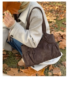 Detail of dark brown faux suede tote bag with pleated texture and silver stud accents