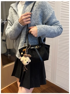 Detalle del bolso hobo de ante negro con hebilla dorada y lindo colgante de perro de peluche