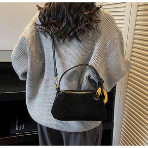Fashionable black suede Boston pillow bag shown with an adjustable crossbody shoulder strap