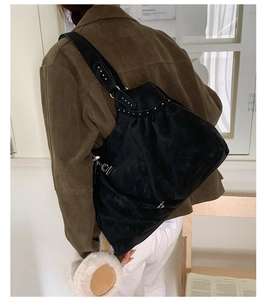 Detailed view of black suede hobo bag with silver rivets on model in retro setting