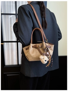 Brown suede tote bag detail featuring dark leather straps and a cute plush bear charm