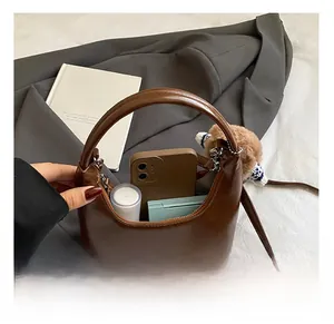 Capacité interne du sac demi-lune marron montrant les essentiels et le pendentif ours doux
