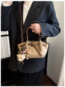 Detail of khaki suede handbag with brown leather handles and cute plush bear charm