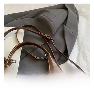 Détail de la bandoulière réglable avec boucle argentée sur sac en cuir PU marron