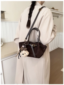 Detalle de bolso tote de ante marrón oscuro con colgante de peluche en modelo elegante