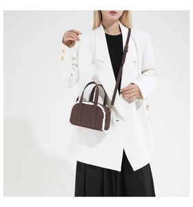 Close-up of brown suede bowling bag with white faux fur trim and gold hardware details