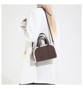 Detail of coffee wool handbag with white plush trim and golden hardware on shoulder strap
