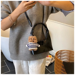 Détail du sac croissant noir brillant avec un joli petit ours en peluche
