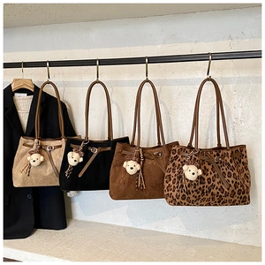 Detail of suede tote bags in various colors with plush bear charms and leopard bow