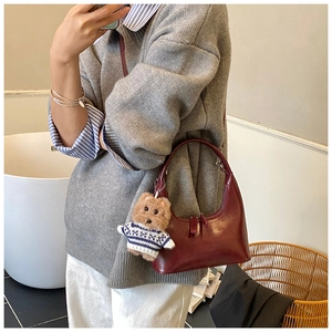 Détail du sac hobo bordeaux en cuir lisse avec un charmant pendentif d'ours en peluche