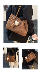 Detail van een bruine suède tote tas met een schattige witte teddybeer hanger