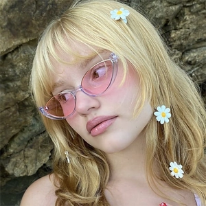 Détail de lunettes œil-de-chat dégradées roses et barrettes marguerites sur modèle blond